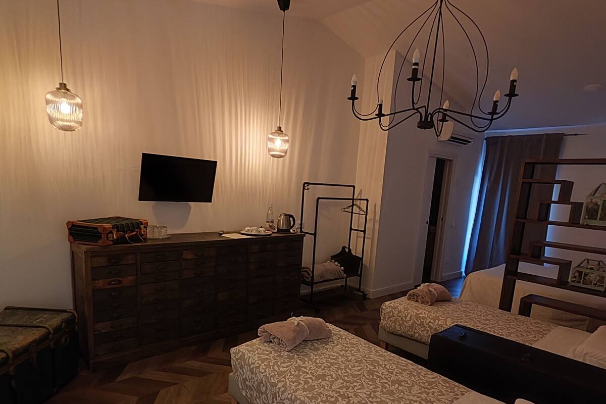 Ett sovrum med två sängar, en byrå, en tv och en kristallkrona.