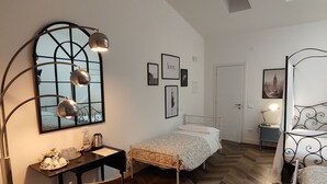 Un dormitorio con suelo de madera con motivo de espiga, dos camas individuales, un escritorio con silla, un espejo grande y obras de arte colgadas en la pared.