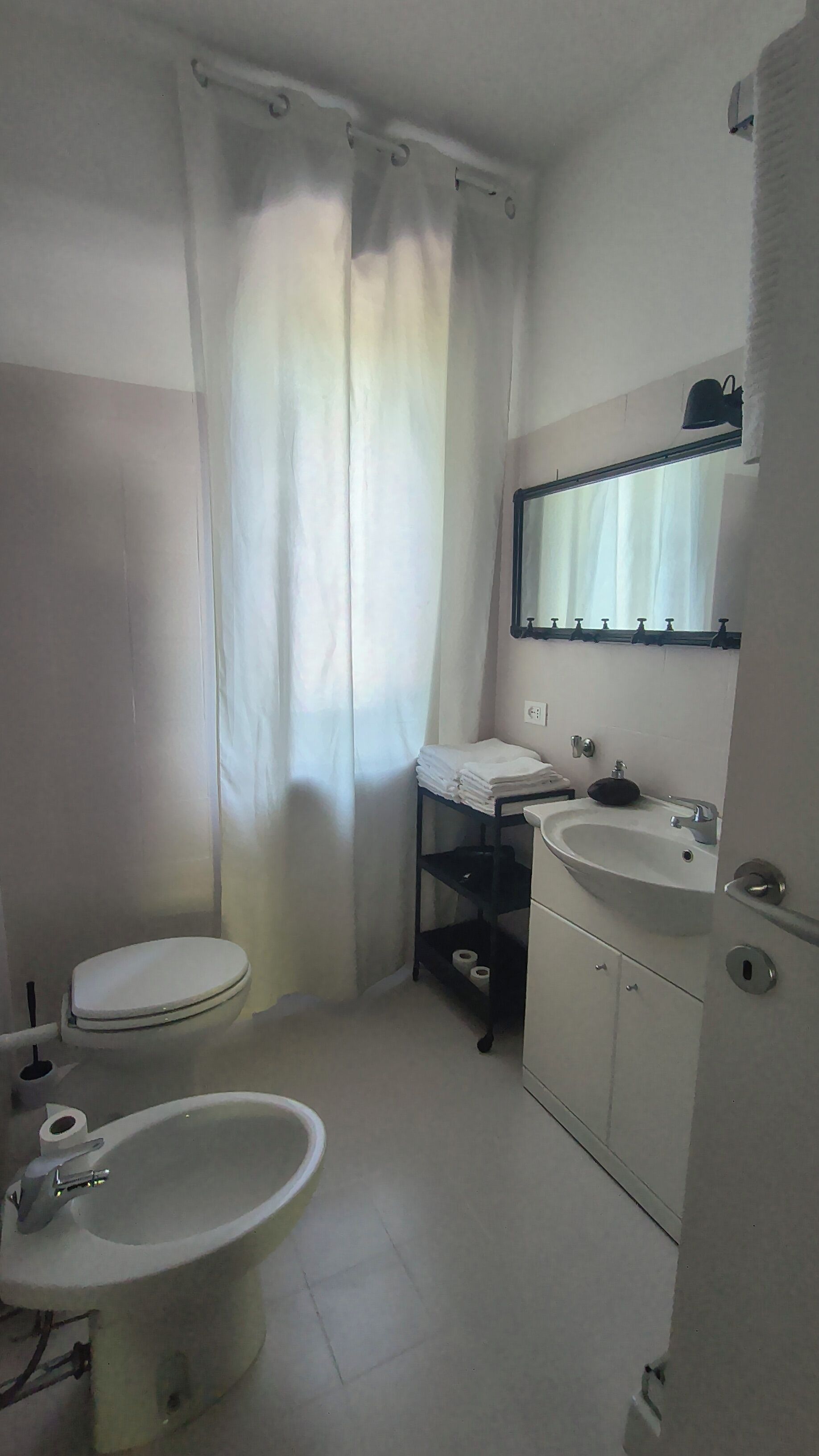 Un baño con inodoro, bidé, lavamanos y cortina de ducha.