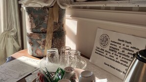 Una mesa con tazas de té, platitos y una tetera, una cesta con estampado floral y un menú.