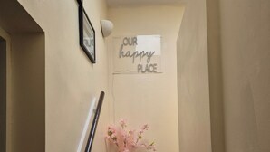 En trappe med et skilt, der siger "OUR happy PLACE", en vase med lyserøde blomster og en telefon på væggen.
