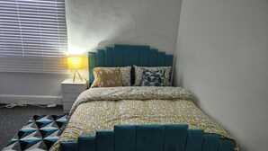 Et pænt opredt soveværelse med seng, sengebord og lampe.