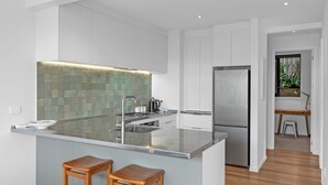 Une cuisine moderne dotée d’un grand îlot central, de meubles blancs et d’un dosseret carrelé.