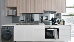 A modern kitchen with built-in appliances, a dishwasher, and a washing machine. - 2-Bed City Escape with Mountain Views (Cape Town)