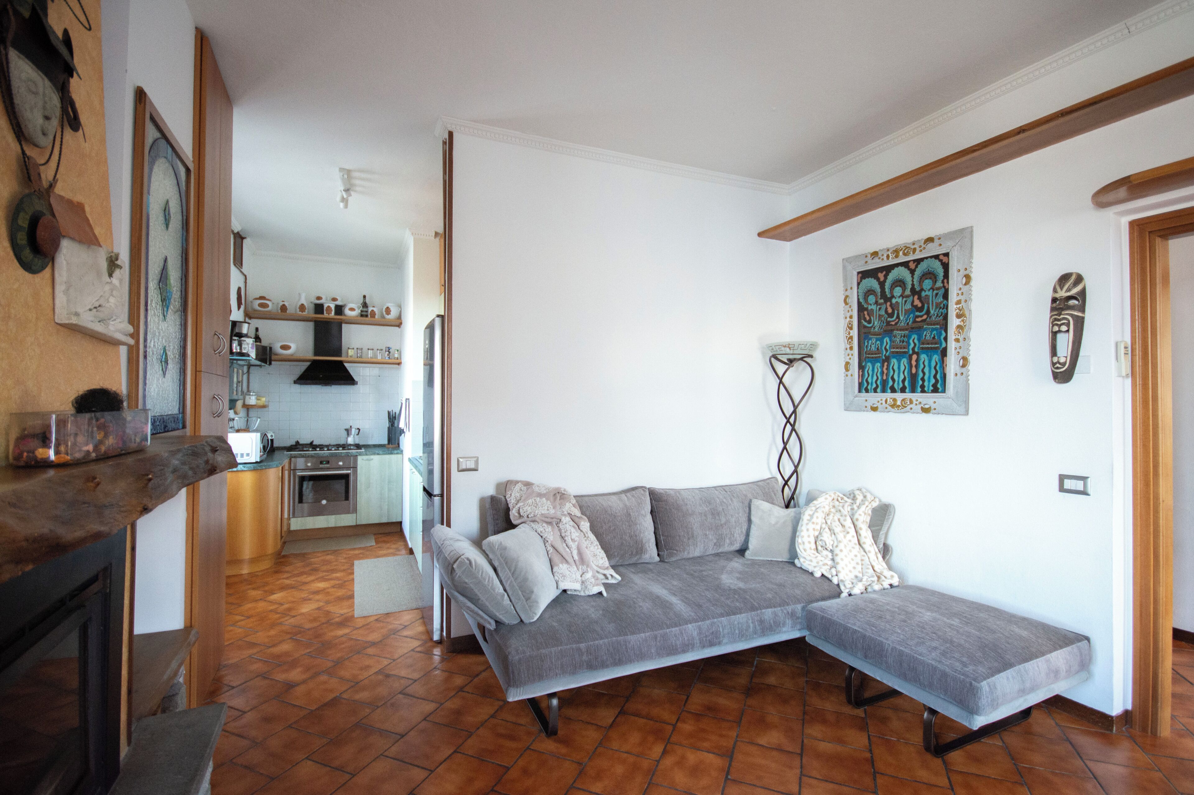 A modern kitchen with a dining area, a gray sofa, and a decorative wall piece.
