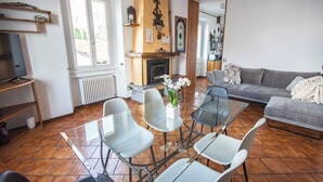 Una sala de estar con chimenea, un sofá, una mesa de vidrio para comer con sillas y un televisor.
