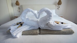 Una cama bien hecha con toallas dispuestas en forma de corazón, un cabecero de madera y un cuadro en la pared.