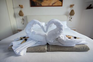 A neatly made bed with towels arranged in a heart shape, a wooden headboard, and a painting on the wall. - Emi's House Lake Como (Lezzeno)
