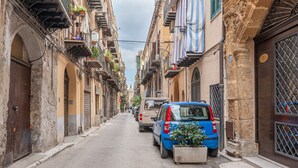 A narrow street lined with historic buildings, some with balconies and plants. - Casa Agli Eremiti by Wonderful Italy (Palermo)