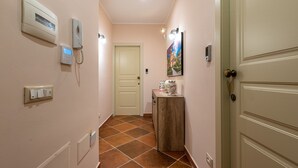 A hallway with a door, a wall-mounted intercom, a light switch, and a small cabinet with decorative items. - Casa Agli Eremiti by Wonderful Italy (Palermo)