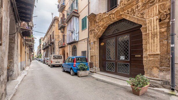 A narrow street lined with historic buildings, parked cars, and potted plants. - Casa Agli Eremiti by Wonderful Italy (Palermo)