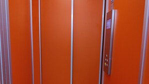 An elevator with orange walls and a metallic door.