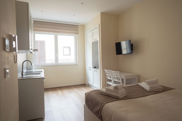 Una habitación de hotel con una cama, un escritorio, un televisor y una ventana.
