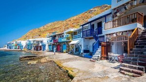 Ein Küstenhaus mit mehreren Balkonen, einer Steintreppe und freiem Blick auf das Meer.
