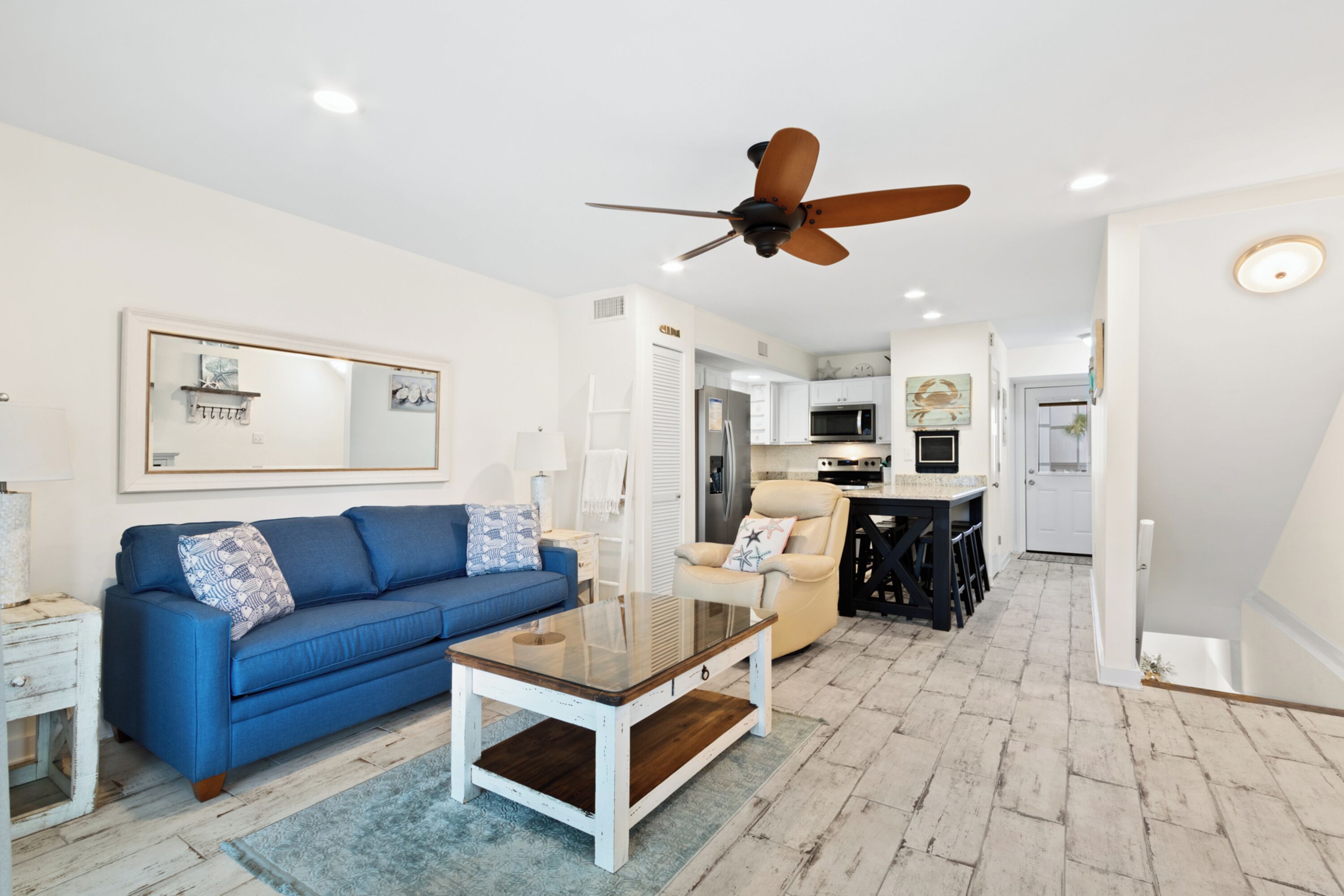 A living room with a blue sofa, a coffee table, and a ceiling fan.