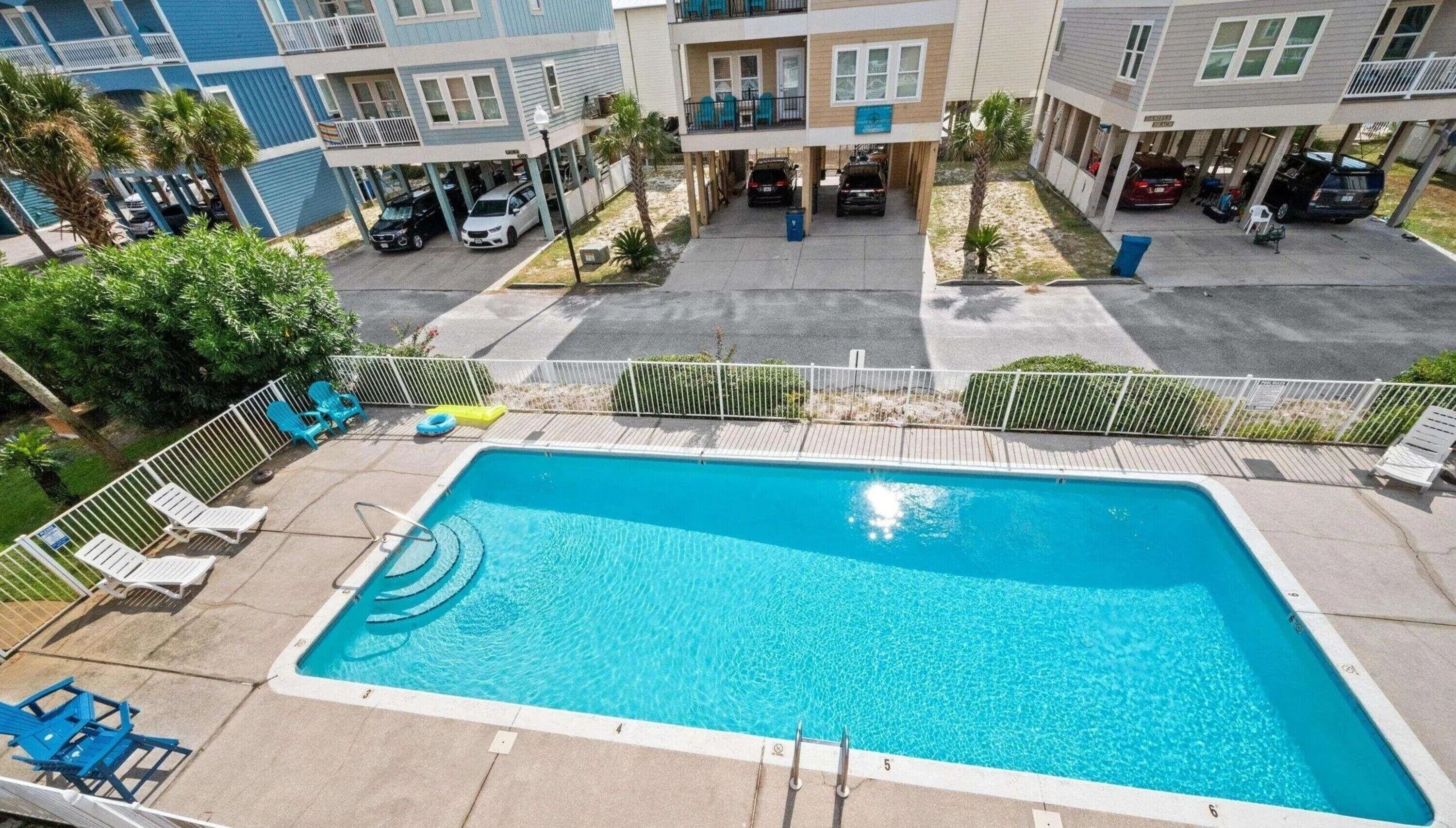 A rectangular swimming pool with a clear blue water, surrounded by a white pool deck.