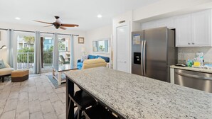 A modern kitchen with a granite countertop, stainless steel appliances, and a ceiling fan. - Laguna Bella B5 (Gulf Shores)
