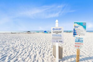 A beach with signs indicating beach safety and personal item removal policies. - Laguna Bella B5 (Gulf Shores)