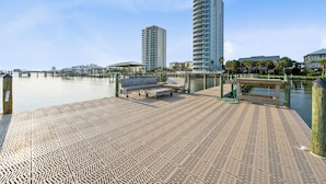 A waterfront promenade with a patterned walkway, benches, and a view of tall buildings. - Laguna Bella B5 (Gulf Shores)