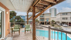 A wooden deck with a pool, a covered area, and a view of neighboring buildings. - Laguna Bella B5 (Gulf Shores)