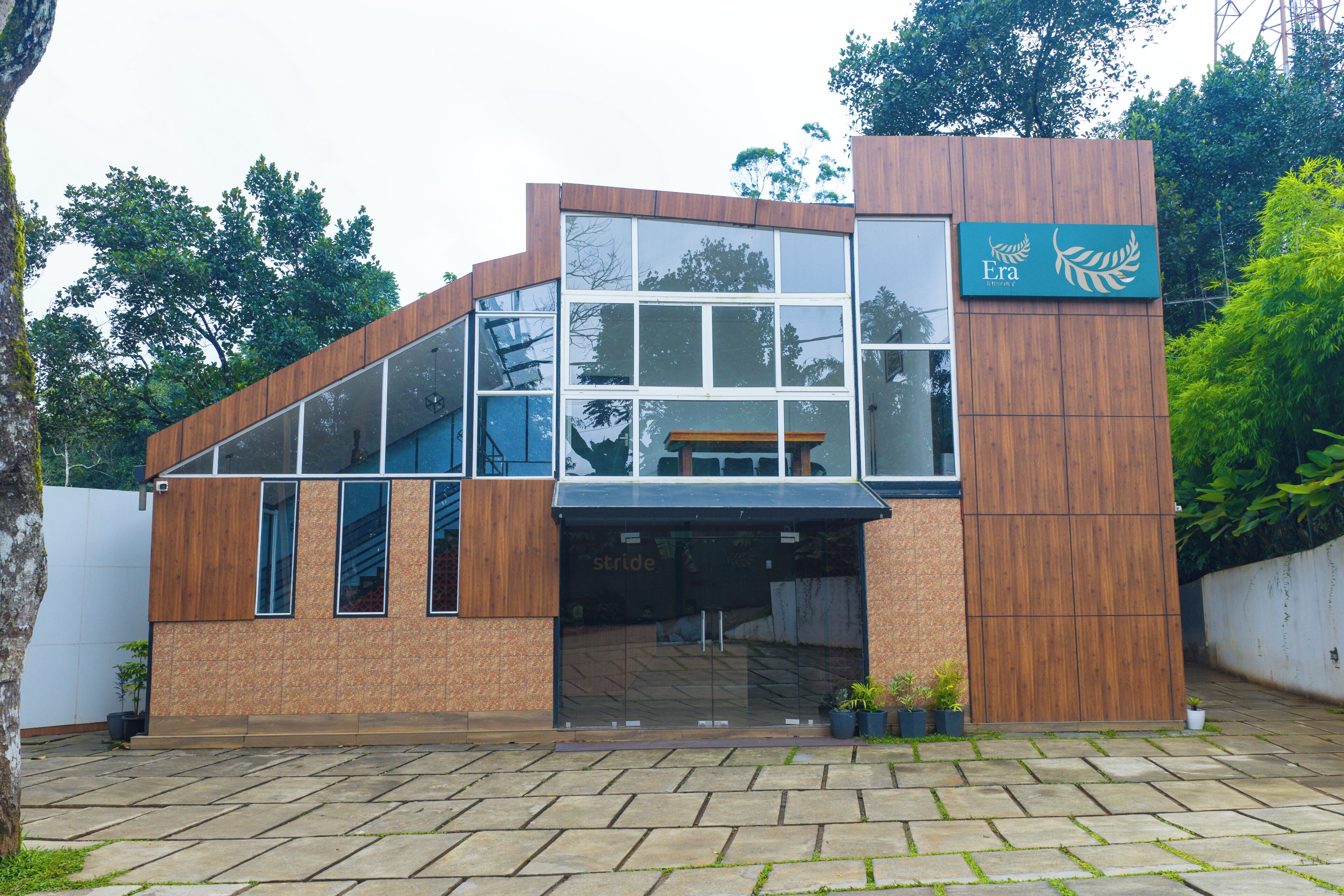 Un bâtiment moderne doté d’une grande façade en verre, de touches de bois et d’une enseigne indiquant qu’il s’agit d’un complexe hôtelier.