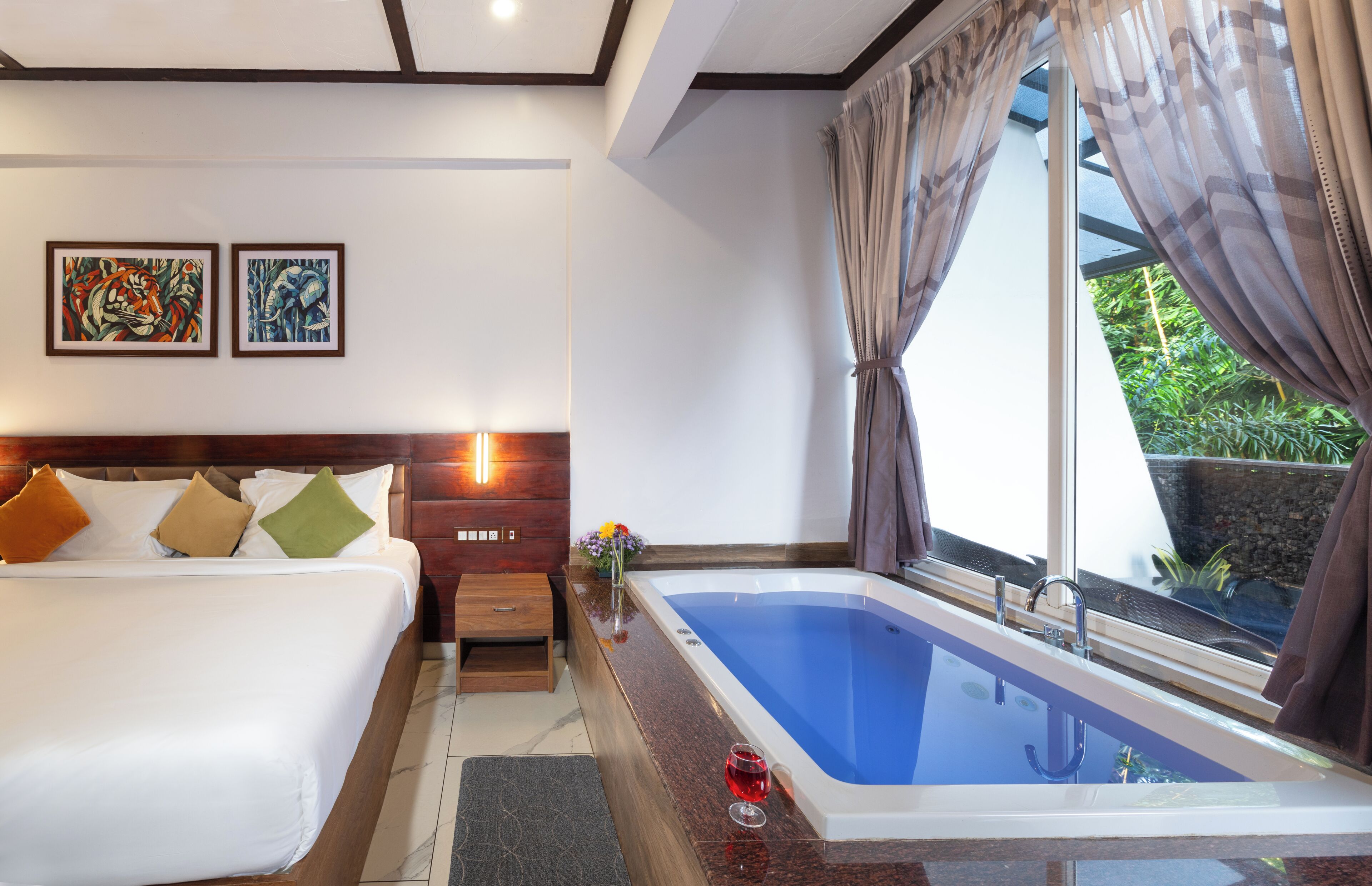 A hotel room with a bed, a nightstand, a bedside table, a large window with curtains, a painting on the wall, and a bathtub.