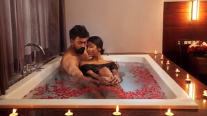 A couple in a bathtub filled with water and rose petals, surrounded by lit candles. - ERA Resort by Stride (Devikolam)