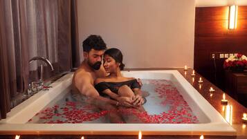 Couples can unwind in a serene bathroom with a large bathtub and candles.