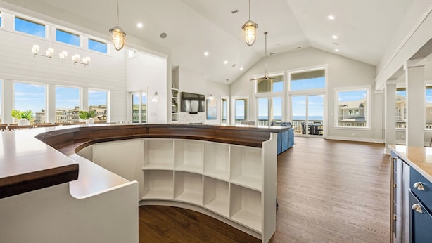 Una cocina amplia con una isla curvada, ventanas grandes y vistas del entorno.