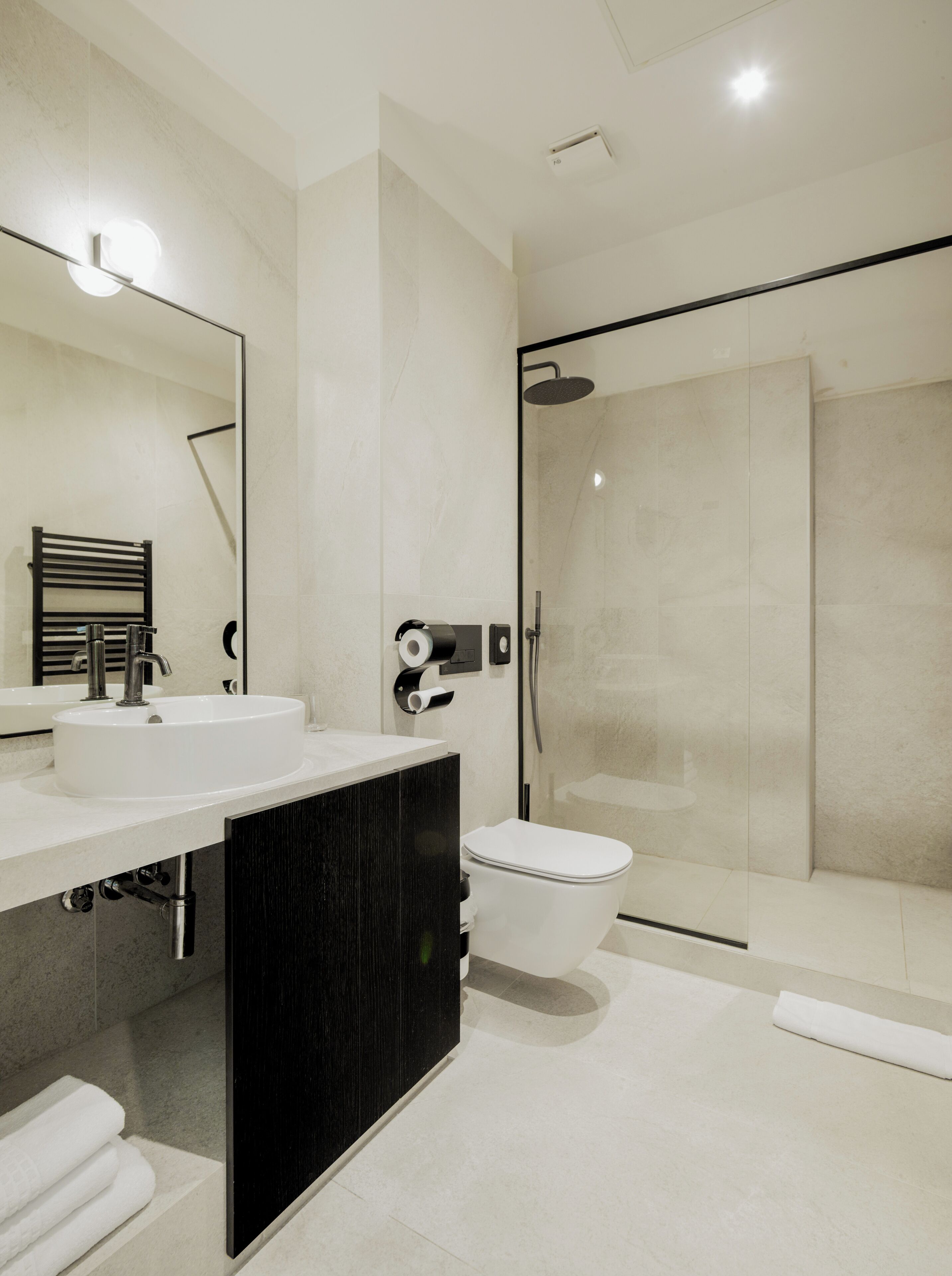 Une salle de bain moderne avec un grand miroir, un lavabo, des toilettes et une douche à parois de verre.