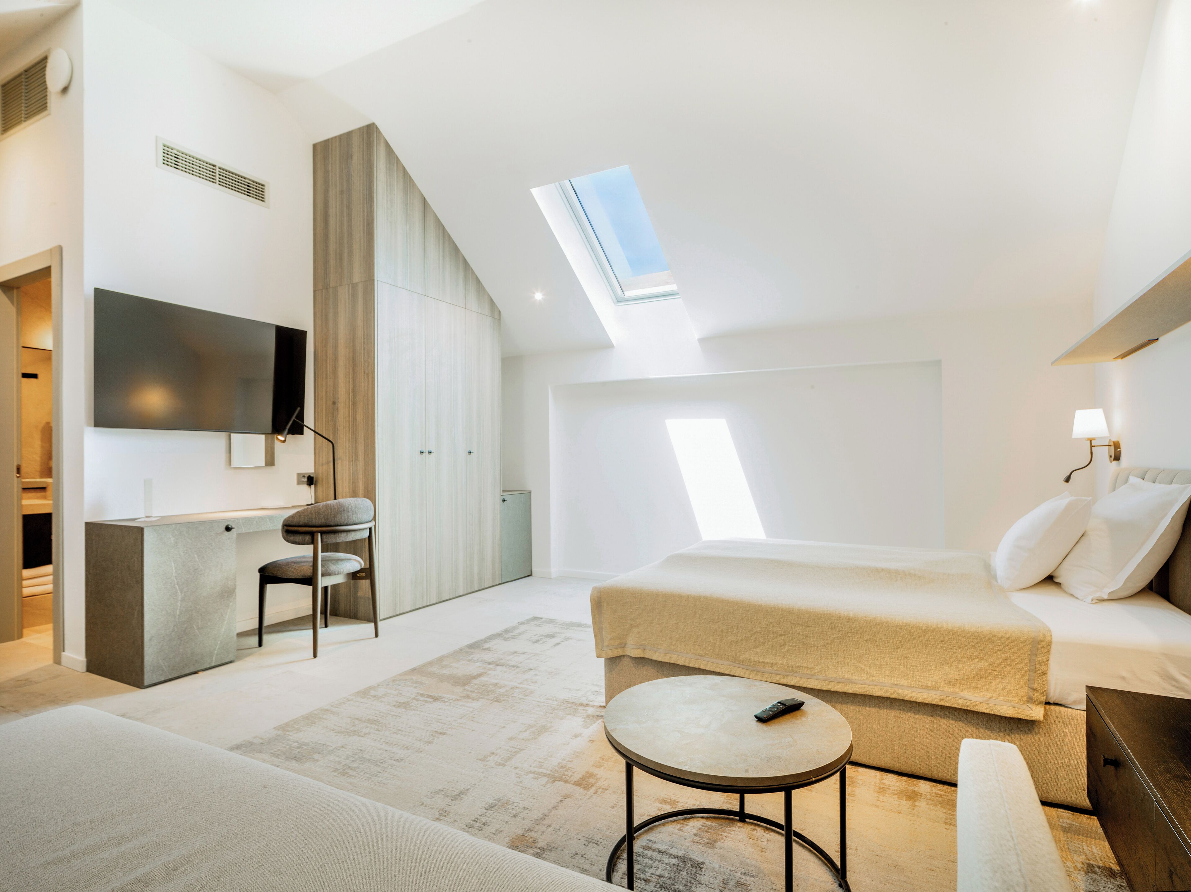 Ein modernes Schlafzimmer mit einem Bett, einem Schreibtisch, einem Stuhl und einem kleinen Tisch.