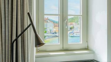 A room with a window seat, a lamp, and a view of a marina.