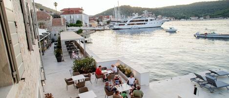 A waterfront patio with outdoor seating and dining areas overlooking a marina with boats.