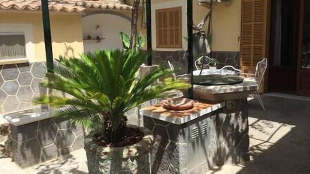 A patio area with a stone planter, a small table with a chair, and a potted plant. - LITTLE HOUSE & GARDEN IN PALMA NEXT TO UNIVERSITY (Palma)