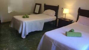 A hotel room with two single beds, a nightstand with a lamp, and a green towel on one bed. - LITTLE HOUSE & GARDEN IN PALMA NEXT TO UNIVERSITY (Palma)