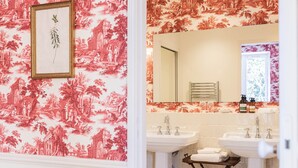 A bathroom with a floral wallpaper, a framed botanical print, two sinks, a mirror, and a window. - Deluxe double room (Le Pian-Médoc)