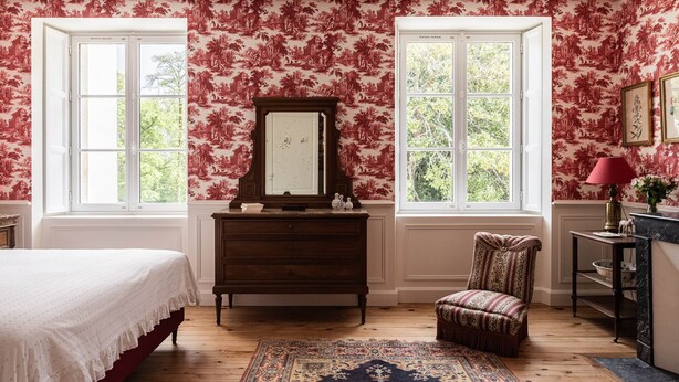 A bedroom with a bed, dresser, chair, and two windows. - Deluxe double room (Le Pian-Médoc)