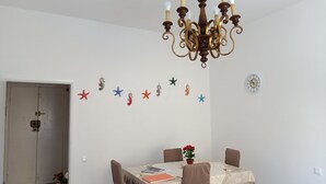 A dining area with a chandelier, a table with chairs, a clock on the wall, and starfish decorations. - Cool apartment with AC in Piombino (Piombino)
