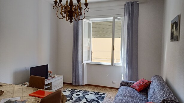 A living room with a sofa, a TV, a dining table, and a patterned rug. - Cool apartment with AC in Piombino (Piombino)