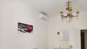 A bedroom with a bed, a dresser, a mirror, a chandelier, and an air conditioning unit. - Cool apartment with AC in Piombino (Piombino)