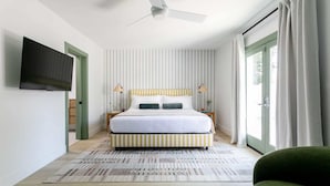 Une chambre moderne avec un lit, un ventilateur de plafond, une télévision et une vue sur l’extérieur.