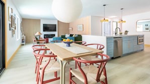 Une cuisine moderne avec un coin repas, comprenant une table en bois, des chaises rouges et un luminaire suspendu.