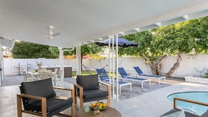 Un espace extérieur abrité comprenant des chaises longues, une piscine et une table à manger.