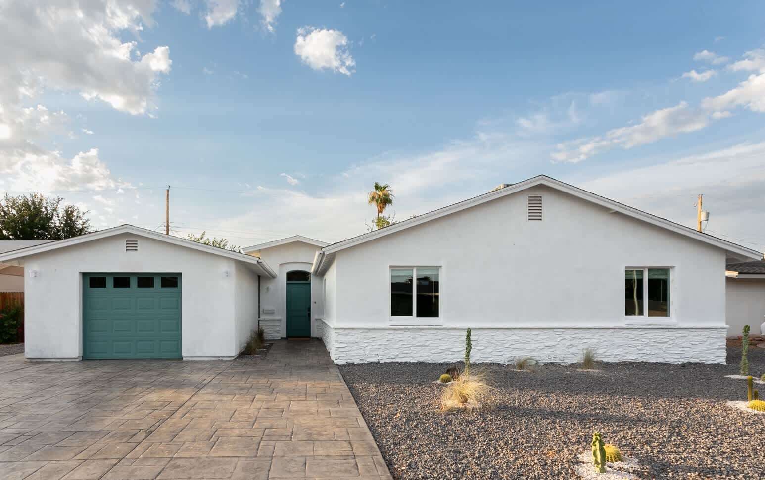 Une maison de plain-pied avec un garage, un petit abri attenant et une allée pavée.