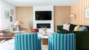 Un salon moderne avec un téléviseur à écran plat, un canapé à rayures vertes et un divan vert.