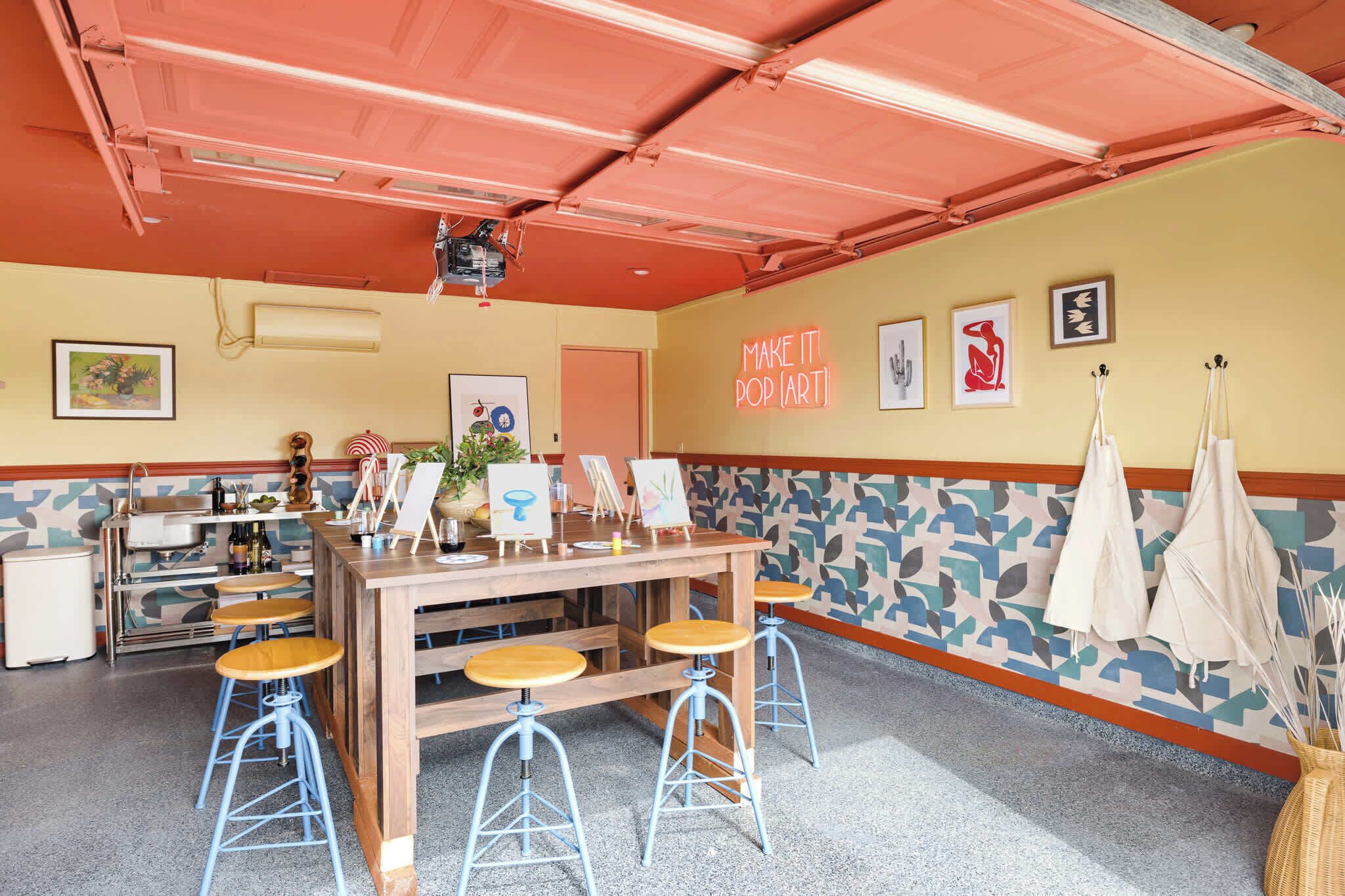 Een restaurant met een houten bar, blauwe krukken en kunstwerken aan de muren.