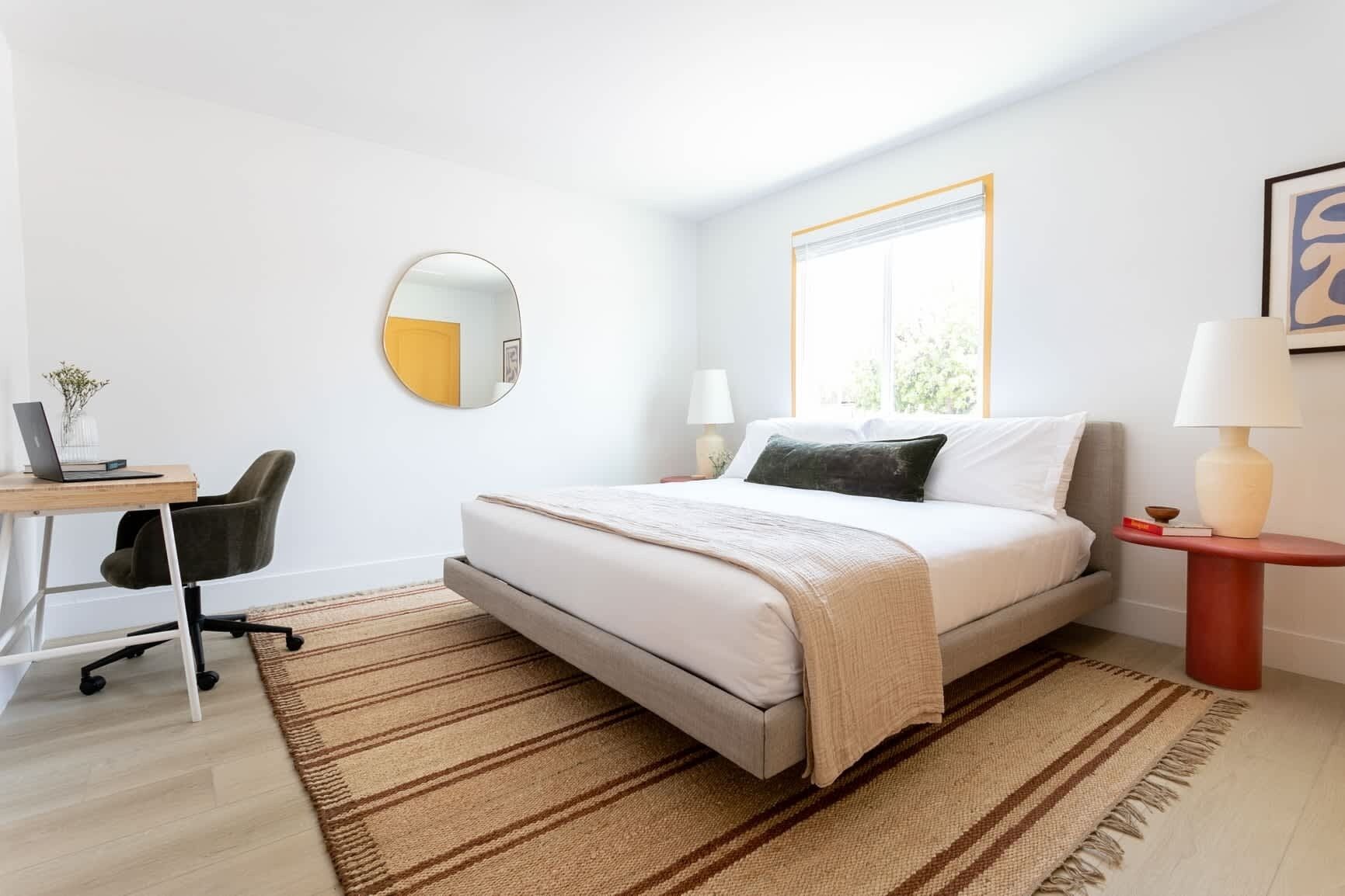Une chambre moderne avec un lit, un bureau, une chaise et une fenêtre donnant sur un beau paysage.