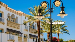 Street lamps, a street sign, and a building with balconies and palm trees. - 11751 Pasetto Ln #306 (Fort Myers)