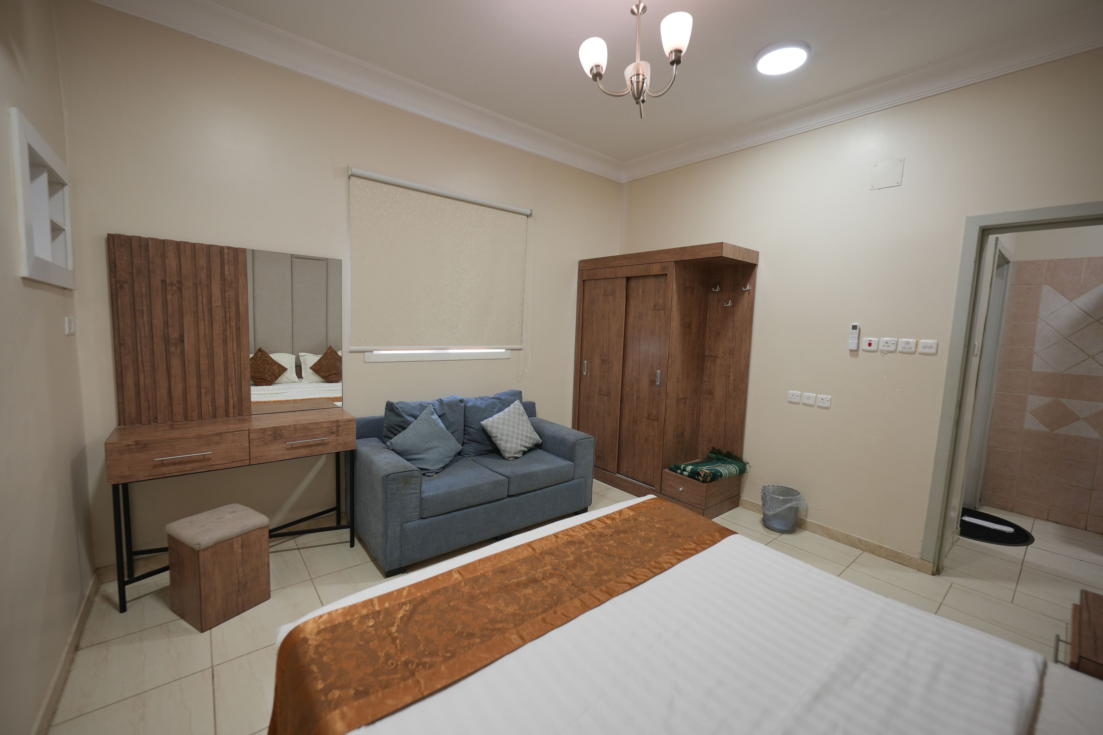 A bedroom with a bed, a desk, a sofa, and a wardrobe.