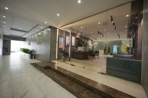 A modern hotel lobby with a reception desk, seating area, and a staircase leading to upper floors. - Amber Serviced Apartments, Al Aziziyah, Riyadh (Riyadh)